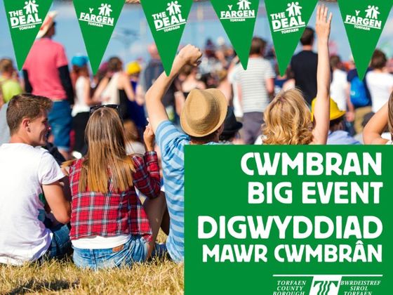 People sitting on bales of hay at an event with branding advertising Cwmbran Big Event