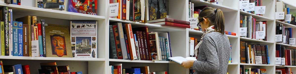 Lady selecting a book from a library shelf