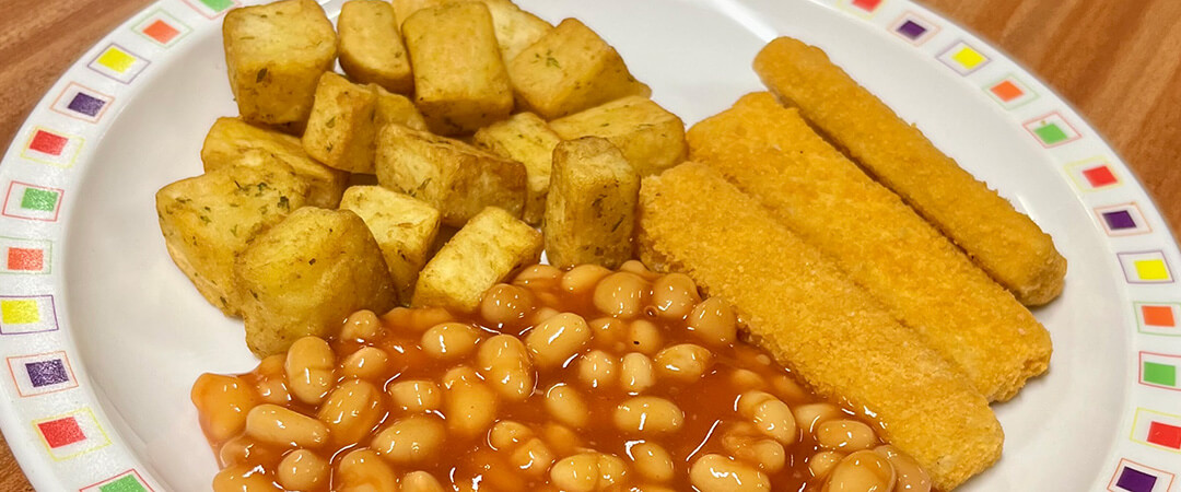 Cod fish fingers served with herby diced potatoes, baked beans and bread and spread