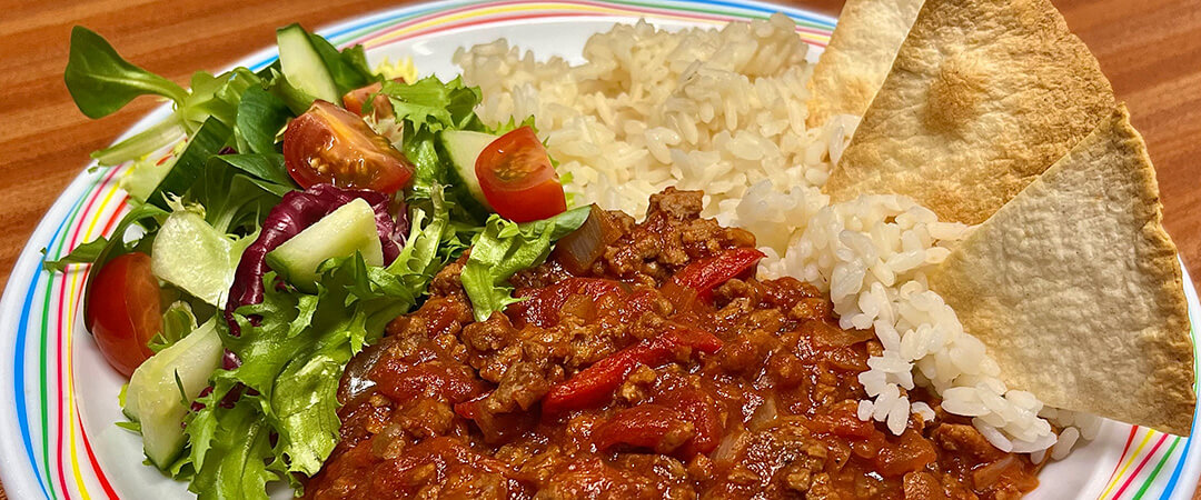 Homemade BBQ beef served with rice, tortilla chips and salad