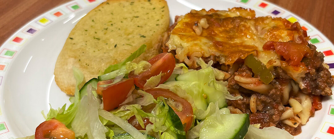 Homemade bolognese pasta bake served with garlic bread and salad