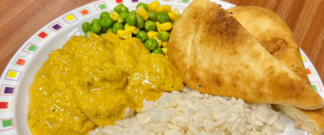 Homemade chicken curry served with rice, peas, sweetcorn and Naan bread