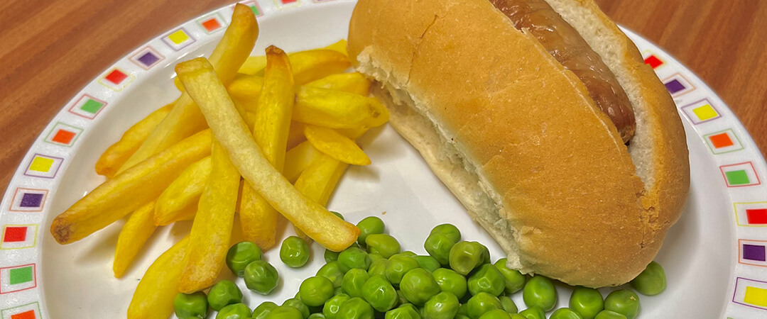 Hotdog served with chips and peas