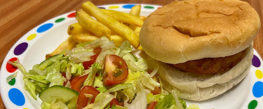 Veggie burger in a bun served with chips and peas