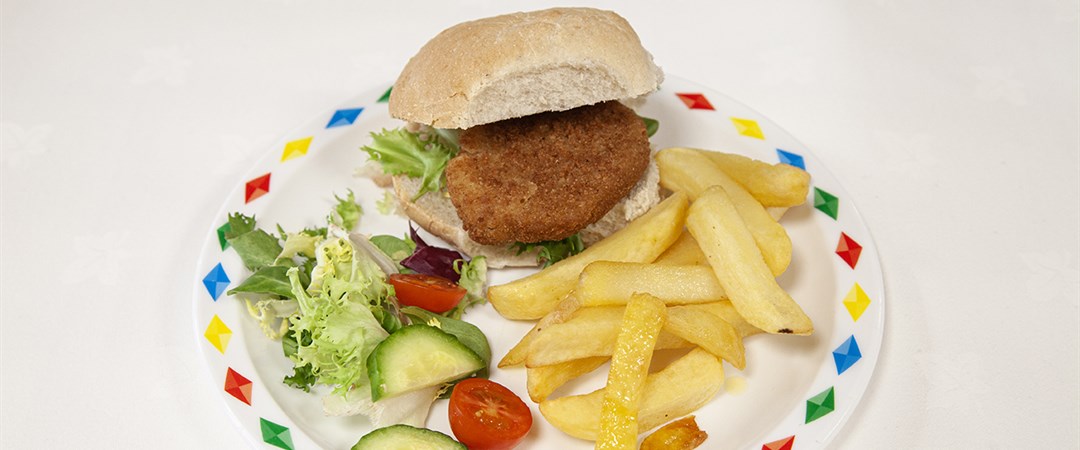 Chicken burger in a bun with chips and salad