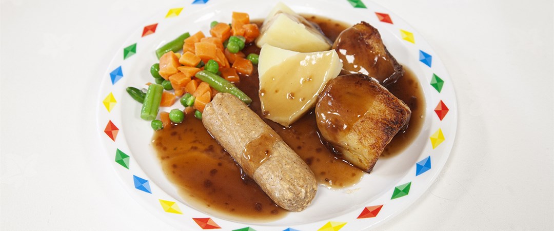 Quorn sausage served with roast and boiled potatoes, selection of veg and gravy