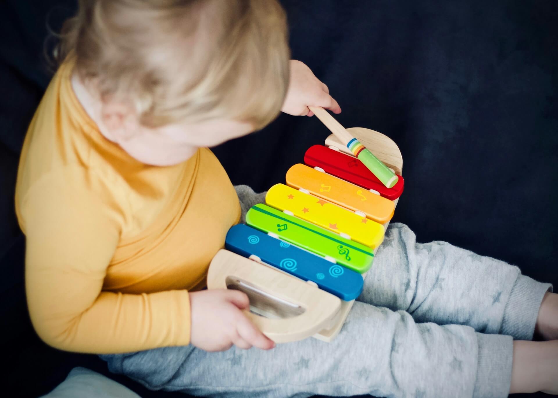 Child playing with colourful toy xylophone     