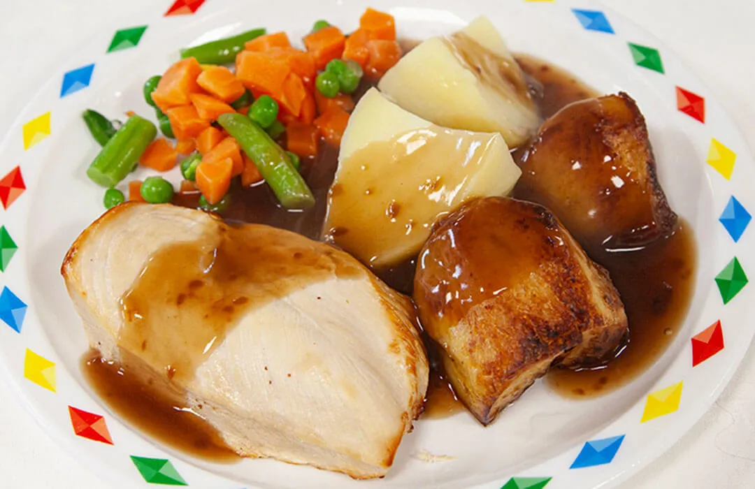 Chicken breast fillet served with stuffing, roast and boiled potatoes, vegetables and gravy