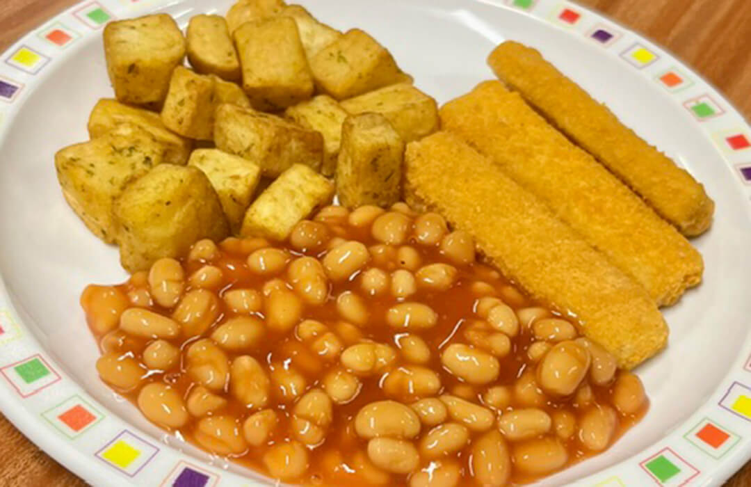 Cod fish fingers served with herby diced potatoes, baked beans and bread and spread