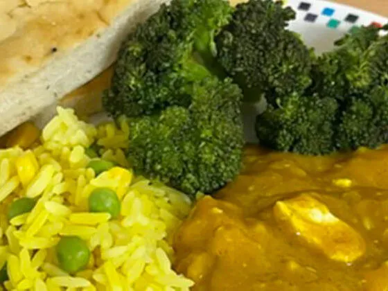 Homemade chicken curry served with rice, peas, sweetcorn and Naan bread