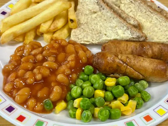 Pork sausage served with chips, peas and sweetcorn or baked beans