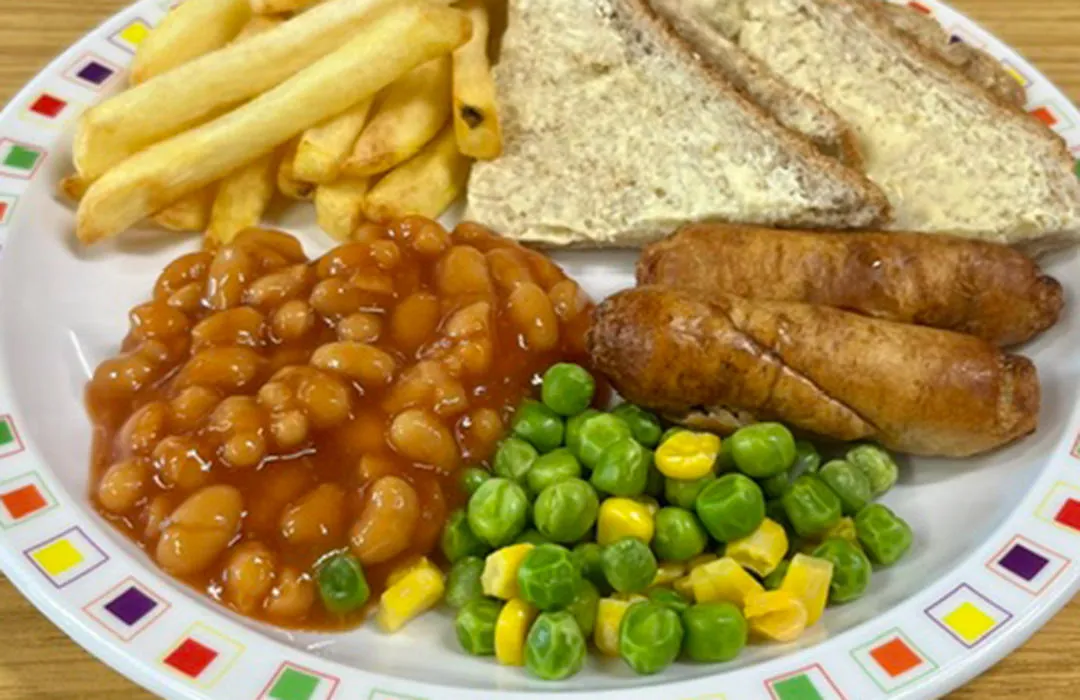Pork sausage served with chips, peas and sweetcorn or baked beans