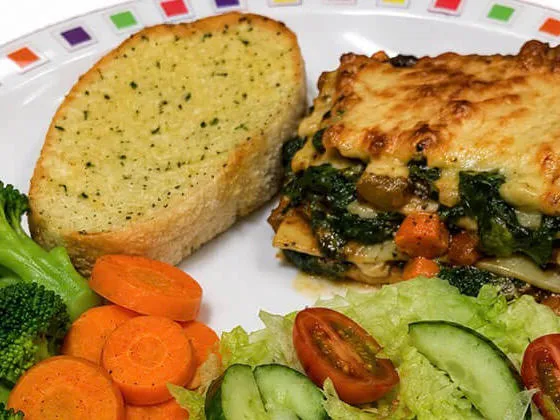 Quorn and spinach lasagne (v) served with garlic bread, vegetables or salad