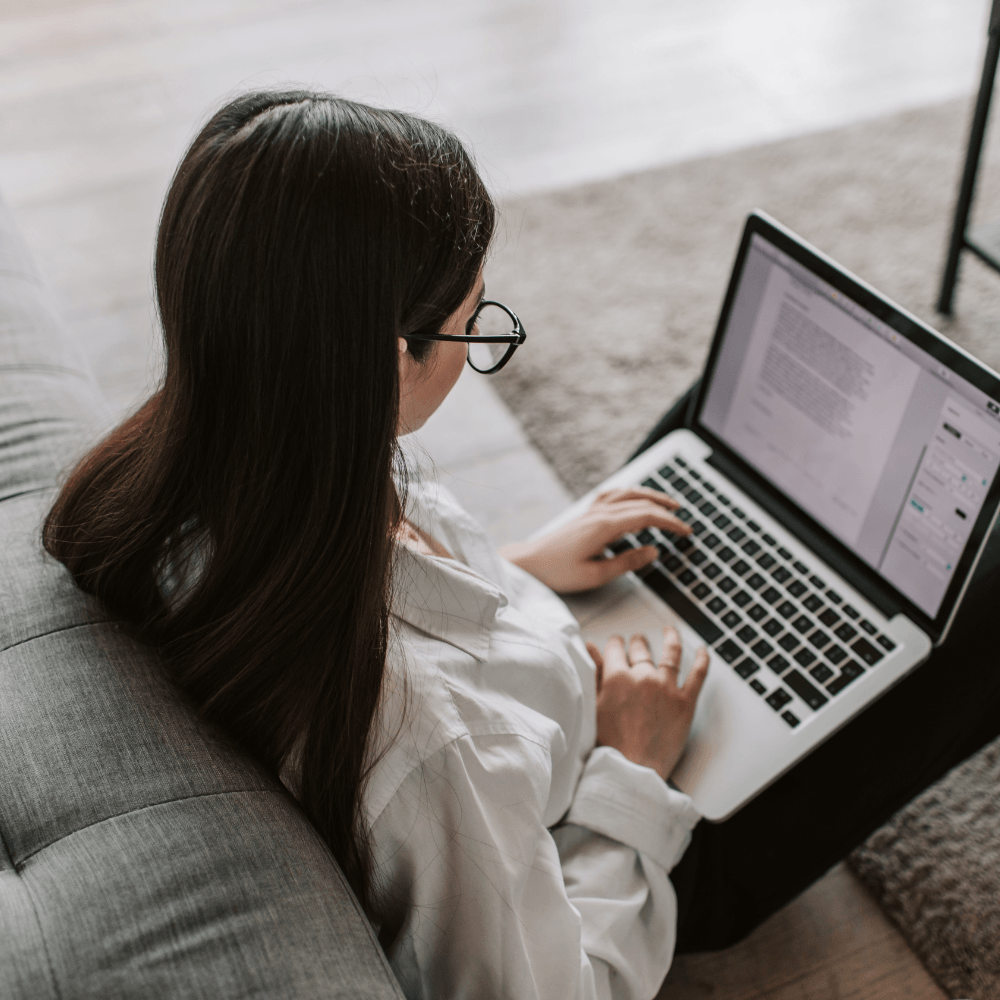 A girl siting on the floor, focused on her laptop