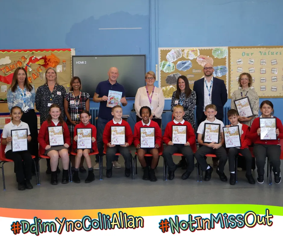 A group of pupils each holding up a copy of the books artwork, alongside teachers and public health staff