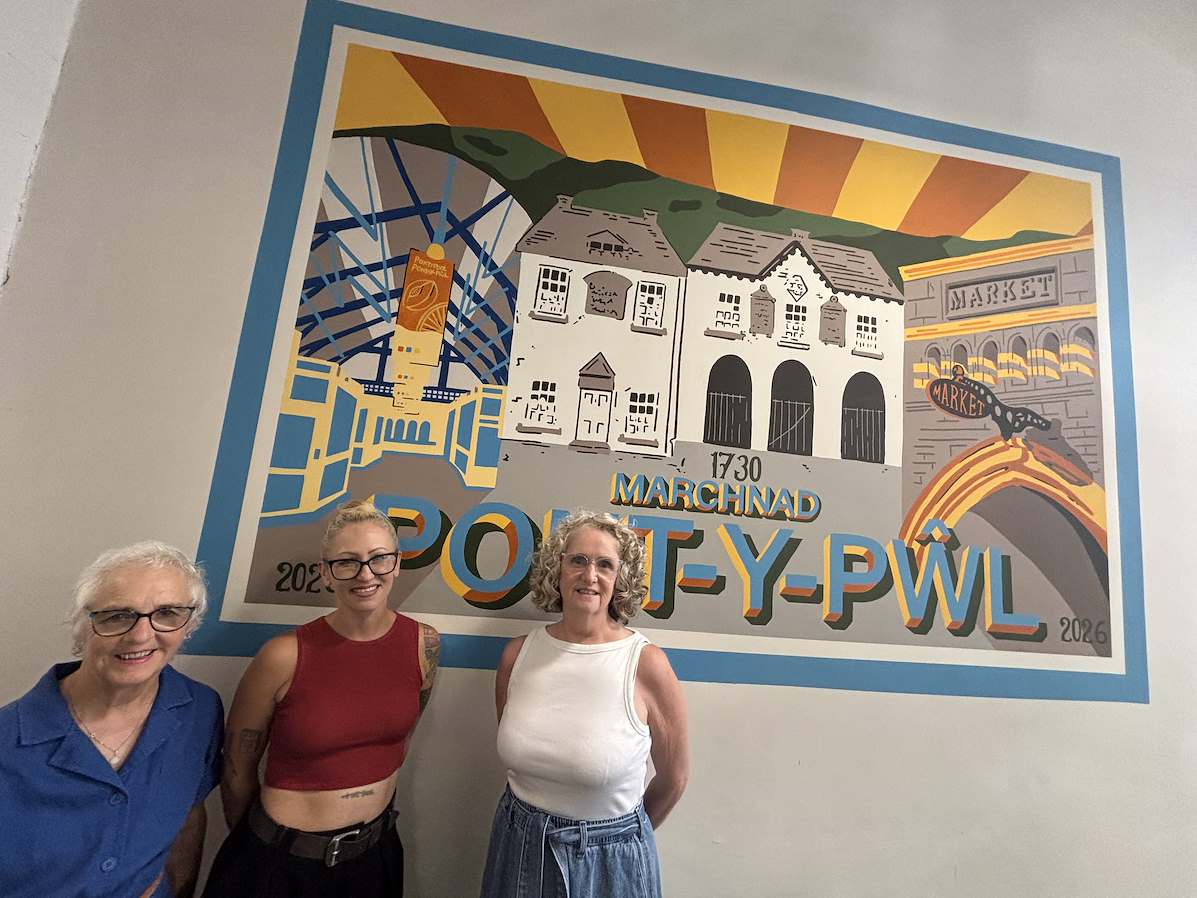  Three people standing in front of a mural featuring local landmarks