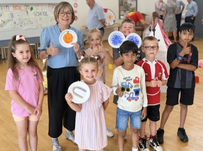 group of children at the food camp in a hall holding up drawings that they made 