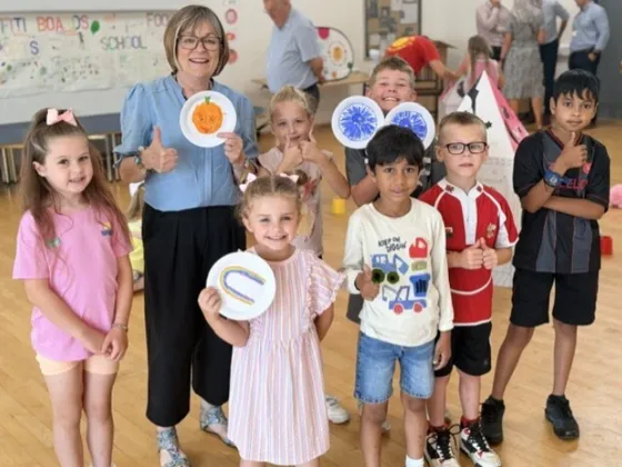 group of children at the food camp in a hall holding up drawings that they made